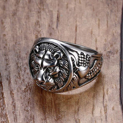 Silver ring with intricate design on a wood grain background
